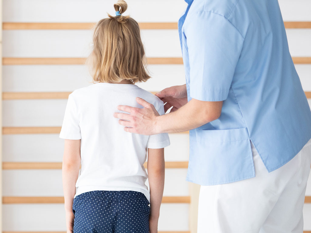 a chiropractor checking the young girl's back