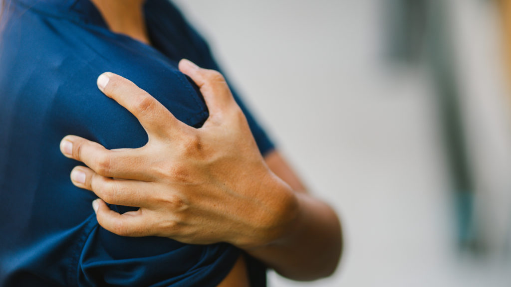 a woman holding her shoulder pain from rotator cuff